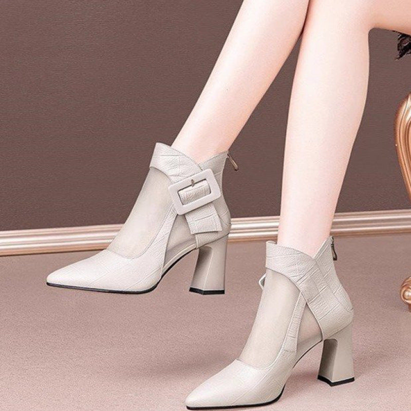 White ankle boots with buckles worn by a person on a neutral background