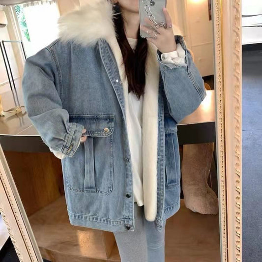 Person wearing a denim jacket with fur lining, taking a mirror selfie.