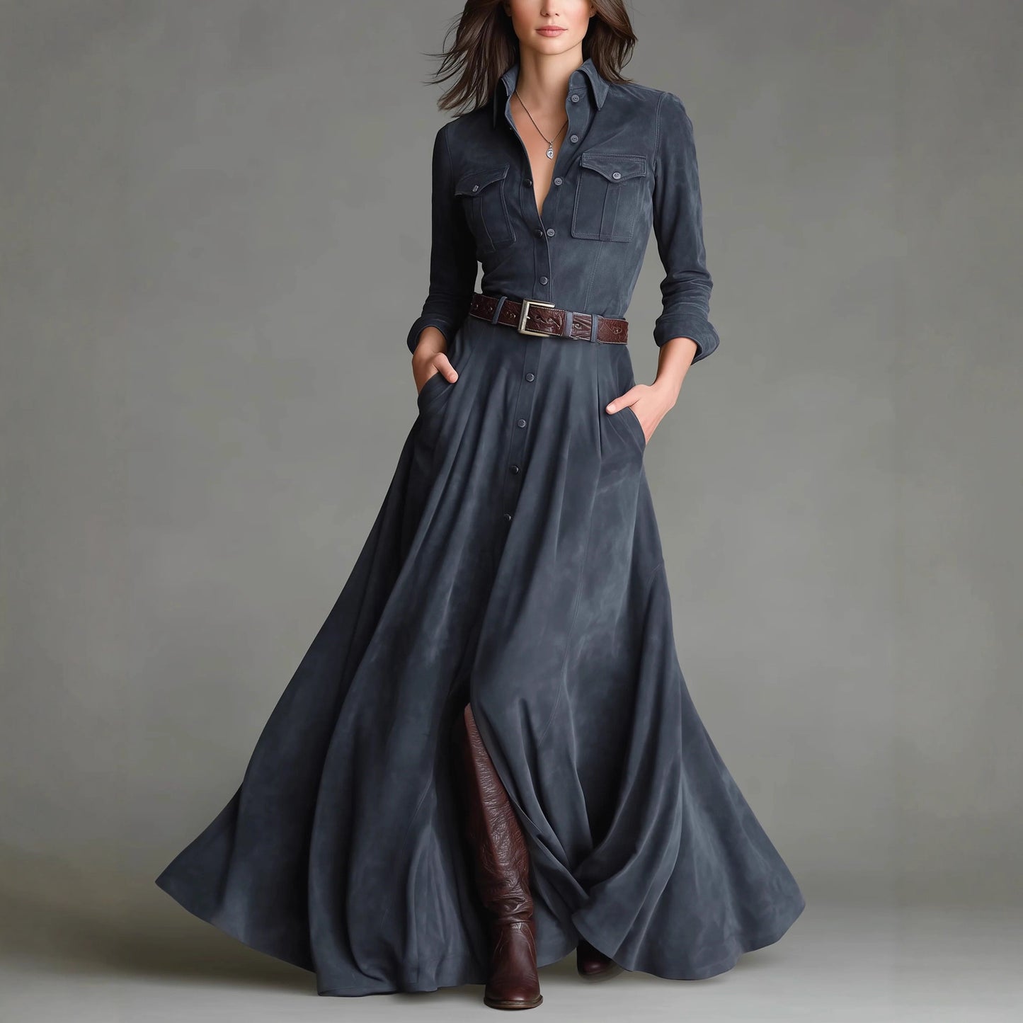 Woman wearing a long denim dress with brown boots against a gray background