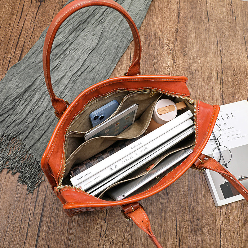 Open orange handbag on a wooden surface with items inside