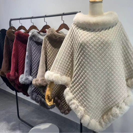 Collection of various textured ponchos on a rack with a white background