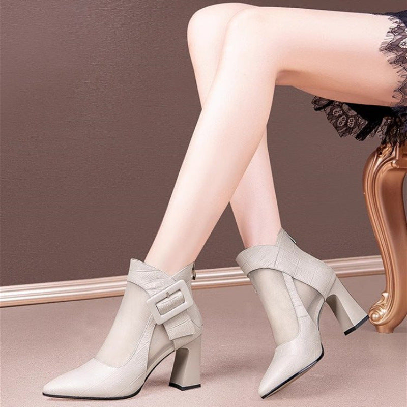 White ankle boots with buckles worn by a person sitting on a chair.