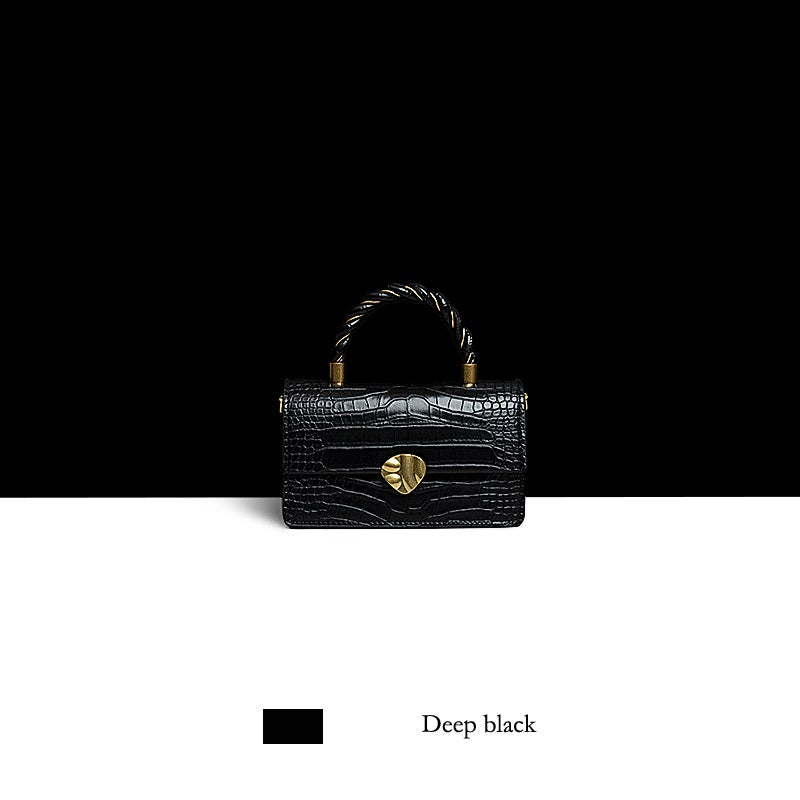 Black handbag with gold heart detail on a black and white background