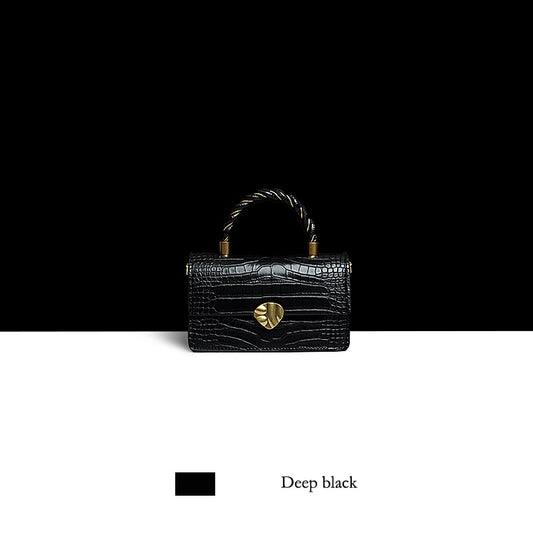 Black handbag with gold heart detail on a black and white background