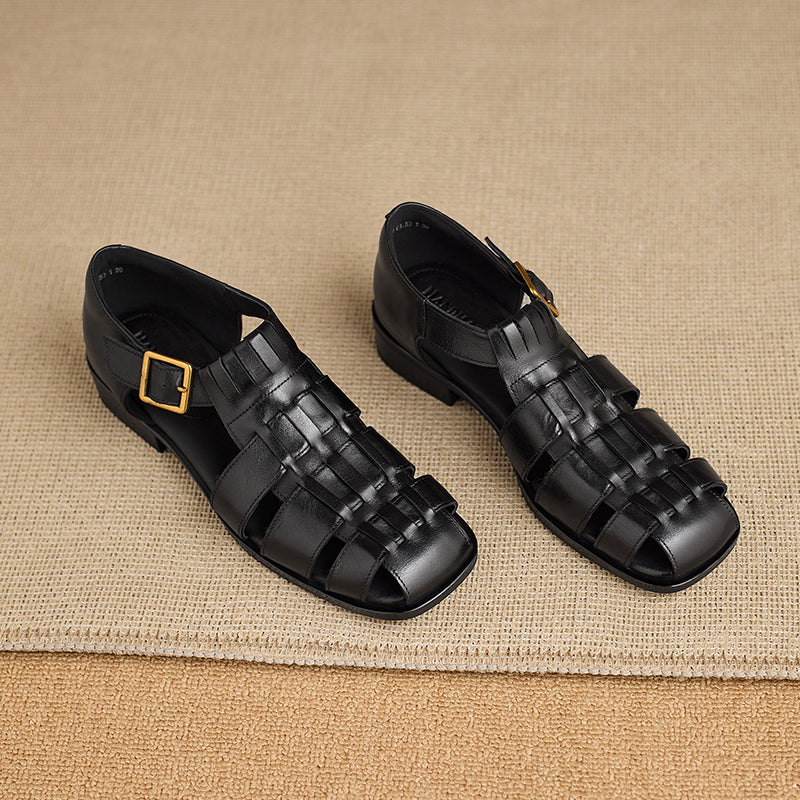 Pair of black woven sandals on a beige fabric background