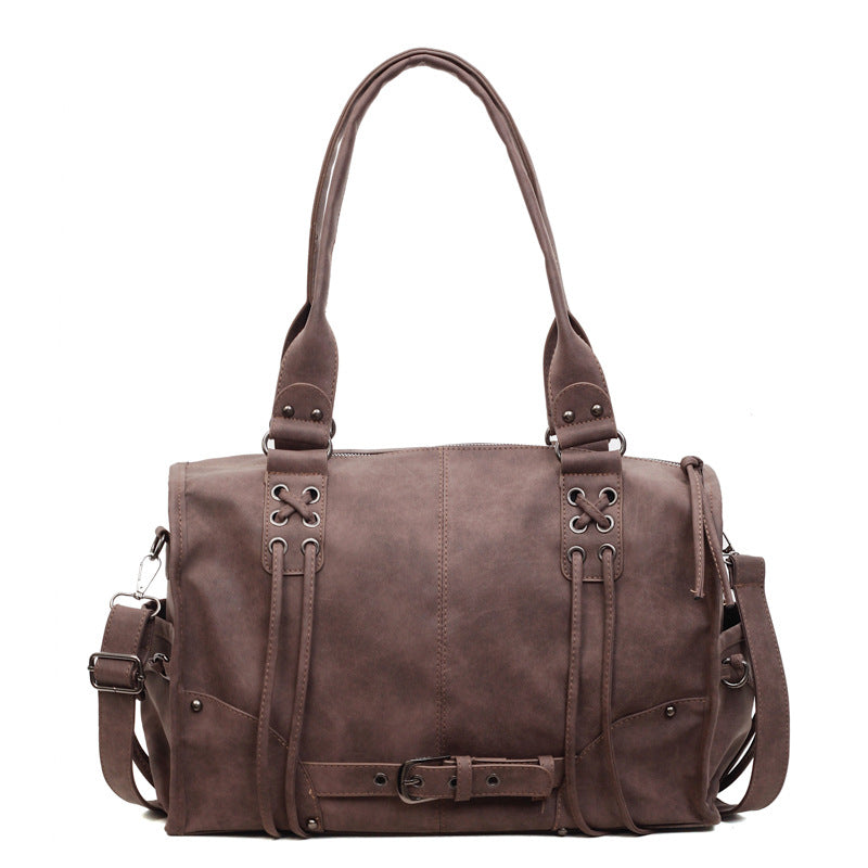 Brown leather handbag with decorative straps on a white background
