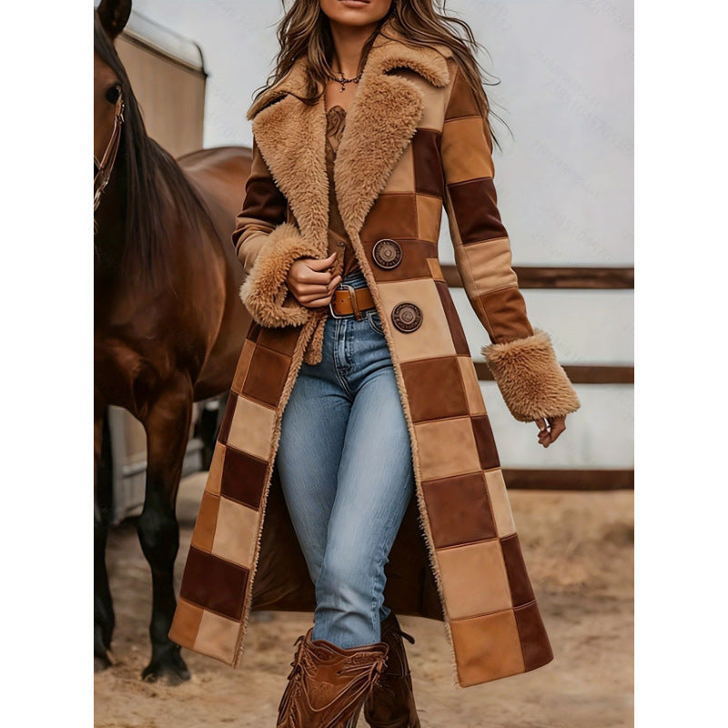 A woman wearing a long patchwork shearling coat in shades of brown and tan, paired with blue jeans and brown boots, standing in front of a horse in a stable setting.