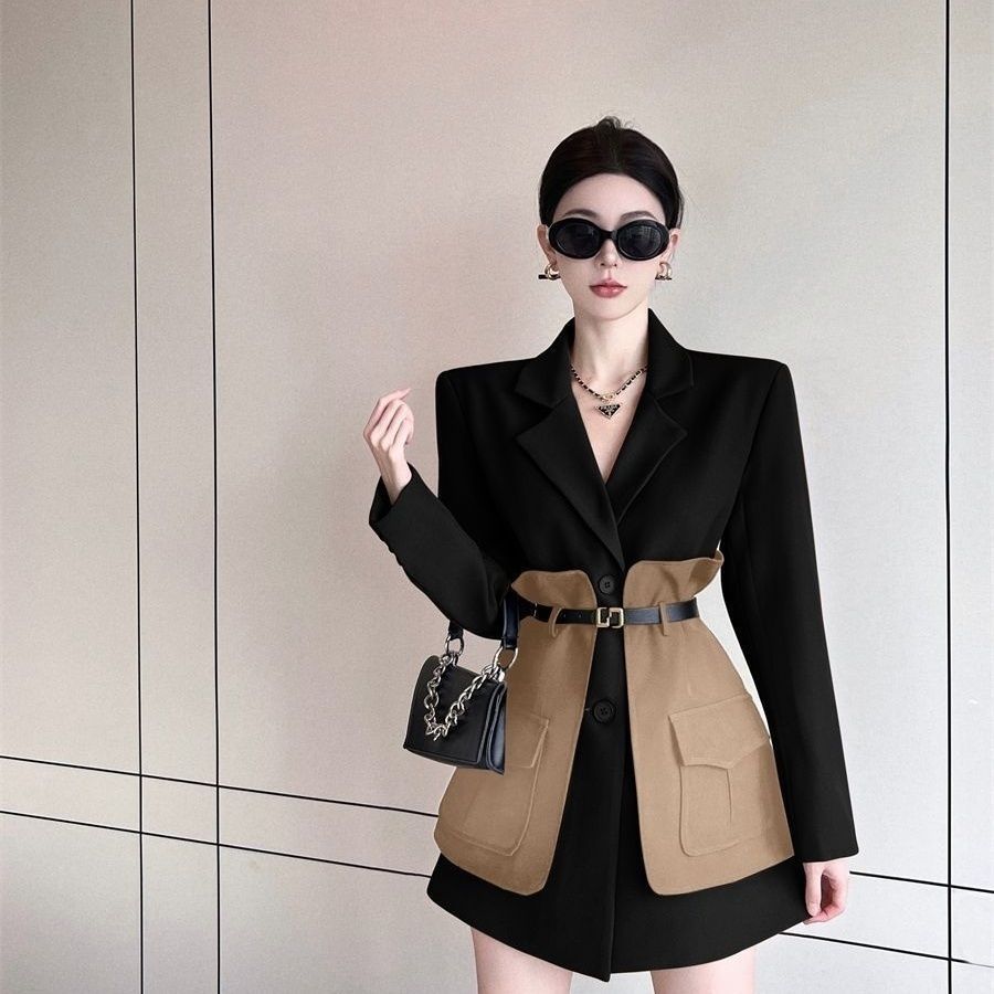 Woman wearing a black and brown two-tone blazer with a neutral background