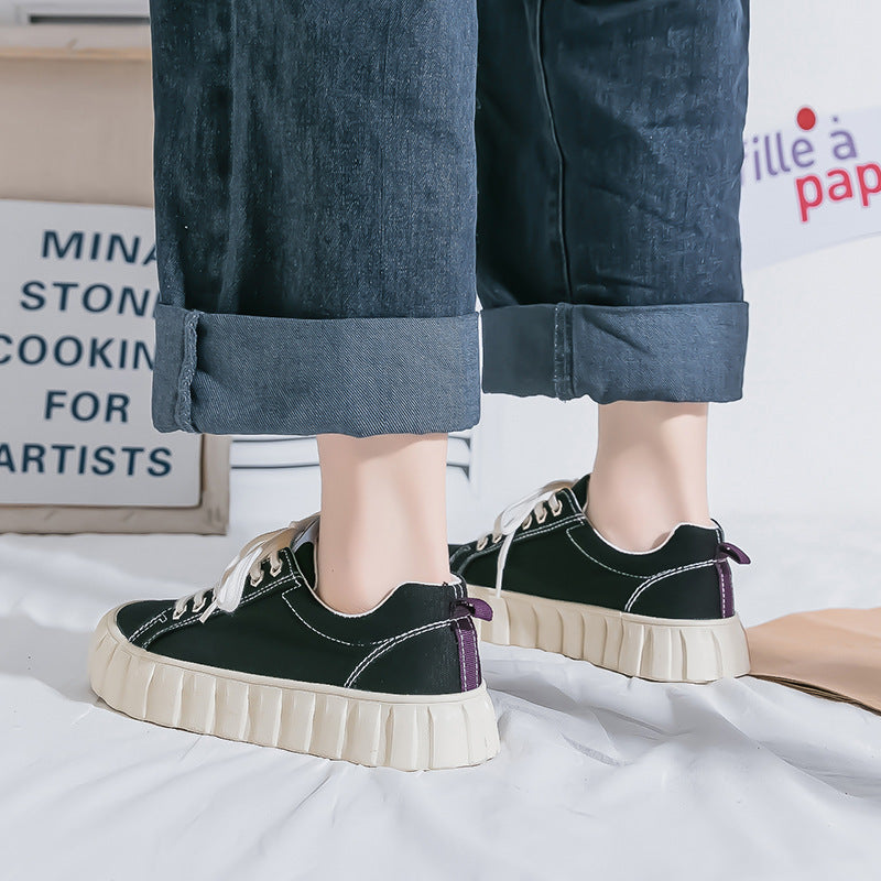 Black sneakers with white soles worn with rolled-up jeans on a light background
