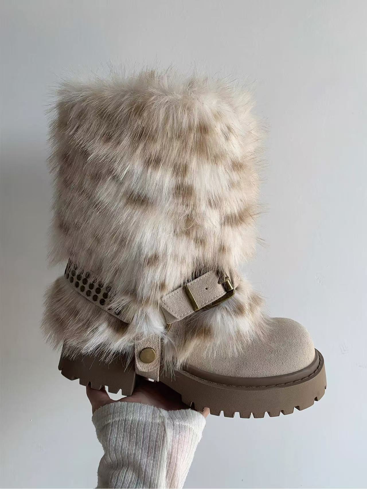Beige winter boots with fur trim held against a plain background