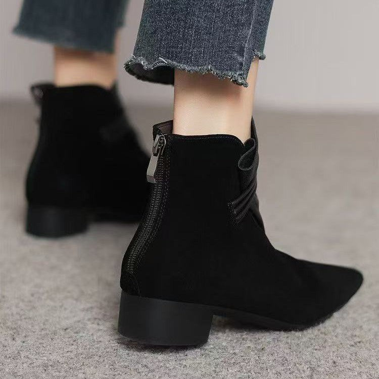Black ankle boots worn with a denim skirt on a neutral background