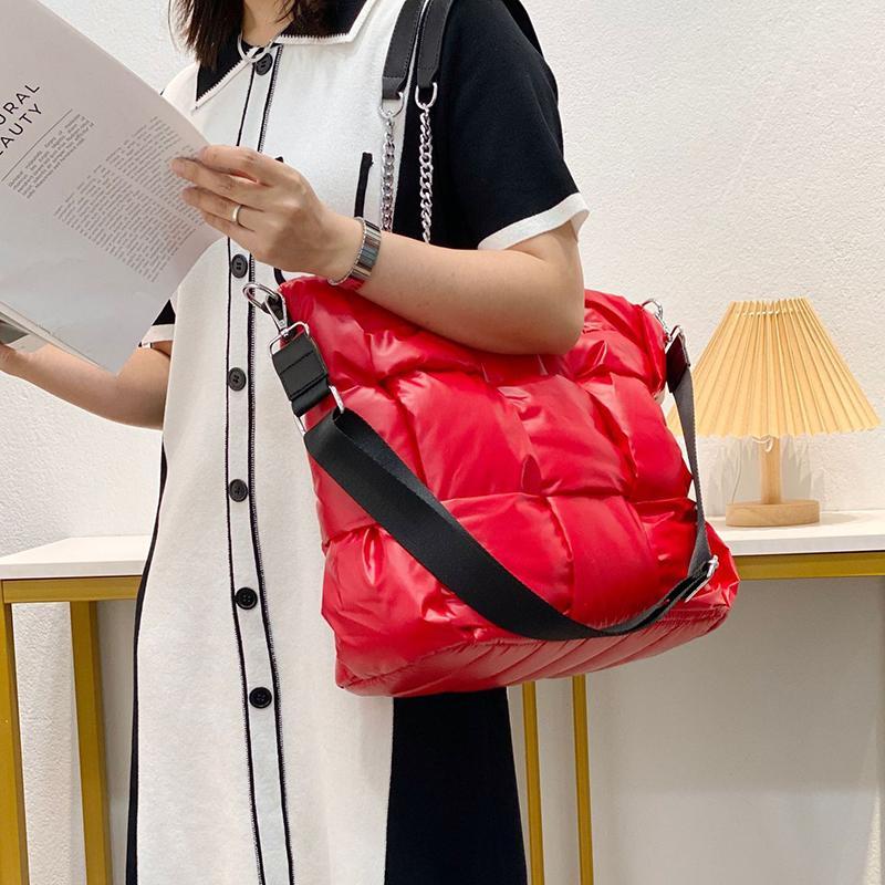 Person holding a red puffer bag and reading a book indoors.