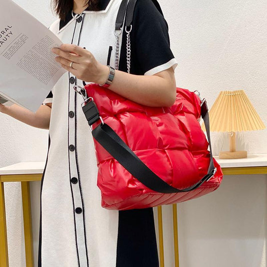 Person holding a red puffer bag and reading a book indoors.
