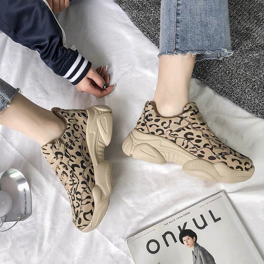 Leopard print sneakers worn by a person on a white surface with a magazine underneath.