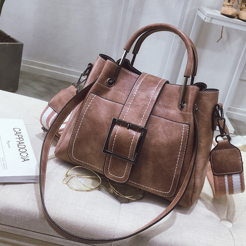 Brown handbag with a buckle on a white surface