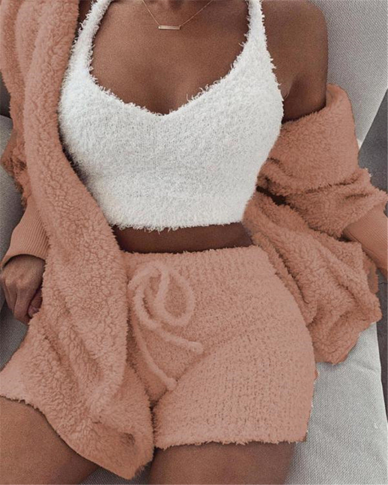 Person wearing a white fuzzy top and pink fuzzy shorts with a brown cardigan.