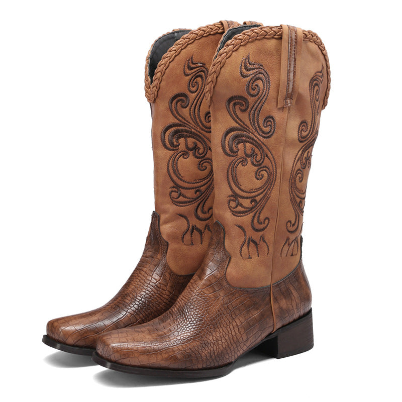Pair of brown cowboy boots with intricate designs on a white background