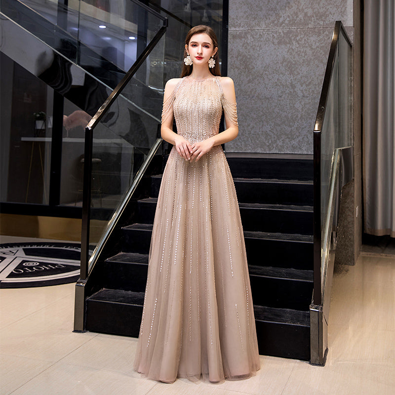Woman in a beige evening gown standing in a stylish interior setting