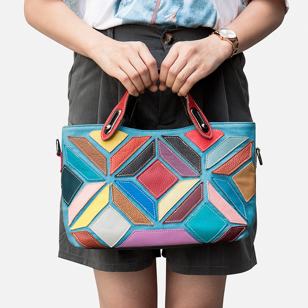 Person holding a colorful geometric-patterned handbag against a plain background