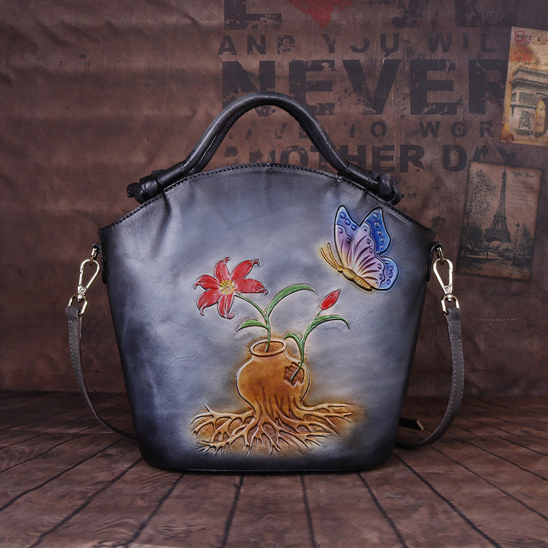 Handbag with floral and butterfly design on a wooden floor.