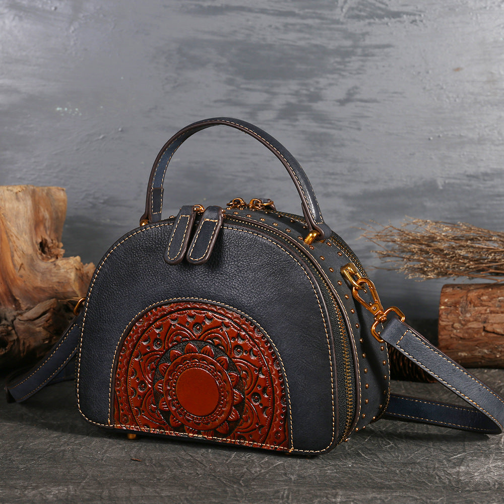 Black handbag with brown decorative panel on a textured surface