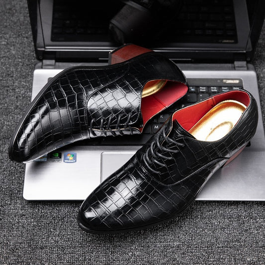 Black crocodile-patterned shoes with red lining on a laptop