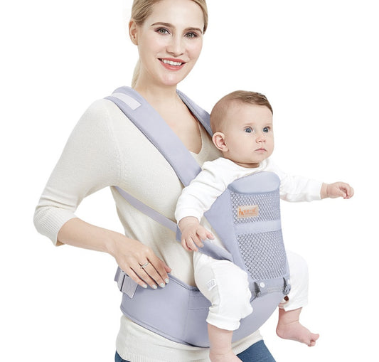 Woman holding a baby in a gray baby carrier against a white background