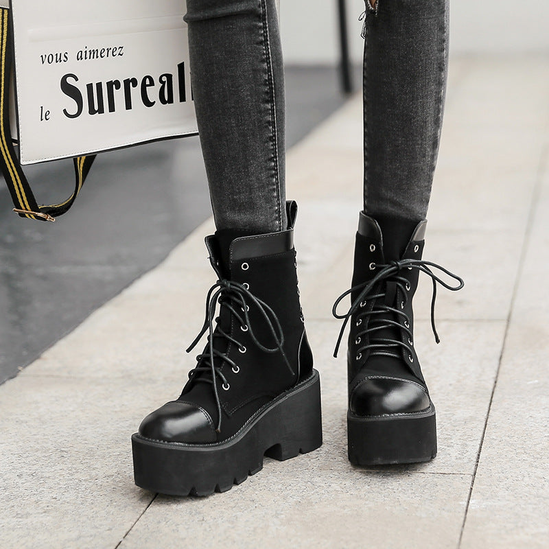 Black platform boots worn with black jeans on a light gray floor.