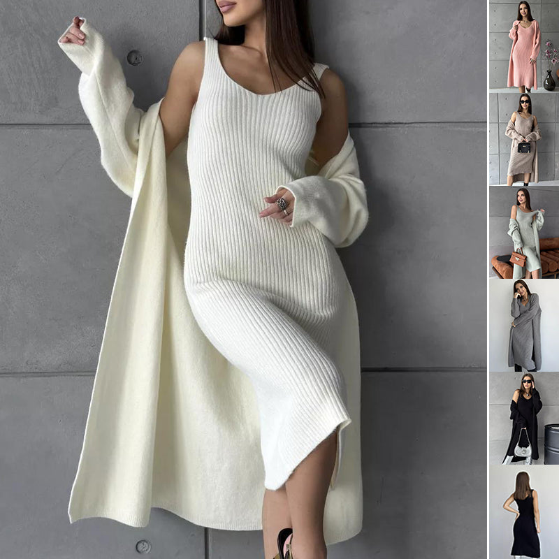 Woman wearing a white ribbed dress with long sleeves against a gray wall.