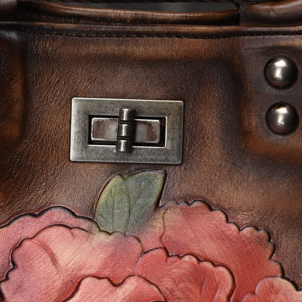 Close-up of a brown leather bag with floral design and metal clasp