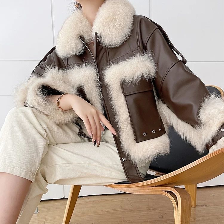 Person wearing a brown leather jacket with white fur trim sitting on a wooden chair.