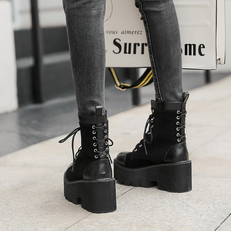 Black platform boots worn with gray pants on a light background