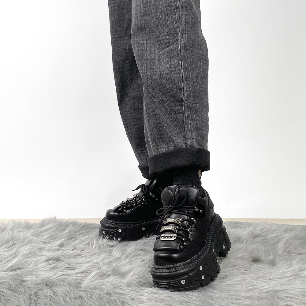 Black platform shoes worn with gray pants on a white background