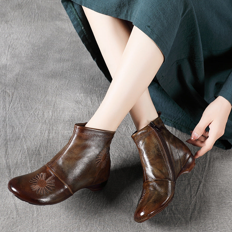 Brown leather ankle boots worn by a person sitting on a gray surface.