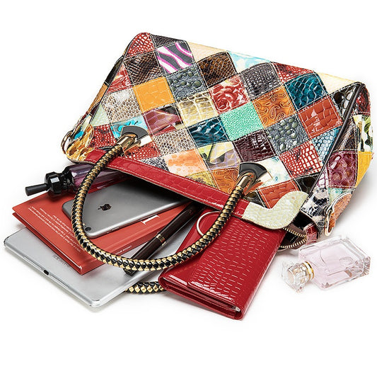 Colorful patchwork handbag with a red interior, containing a phone and other items on a white background.