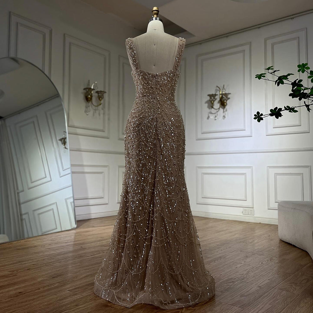 Elegant beaded evening gown on a mannequin in a room with white walls and wooden floor.