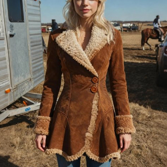 Woman wearing a brown shearling coat in an outdoor setting with a horse and trailer in the background.