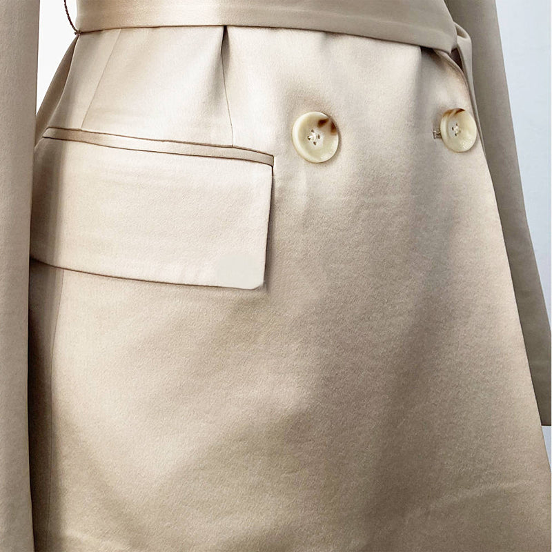 Close-up of a beige skirt with button details on a light gray background by millivan