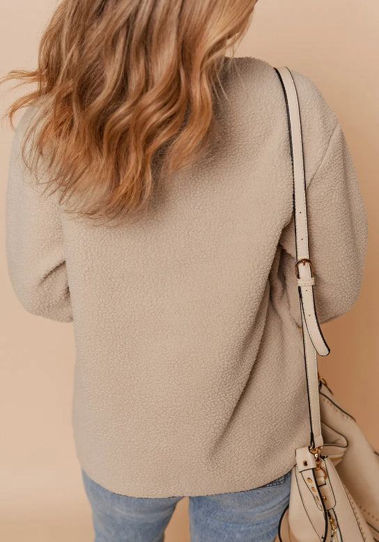 Person wearing a beige sweater with a beige handbag on a beige background