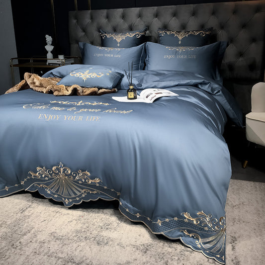 Blue bedspread with gold embroidery on a bed in a bedroom setting.