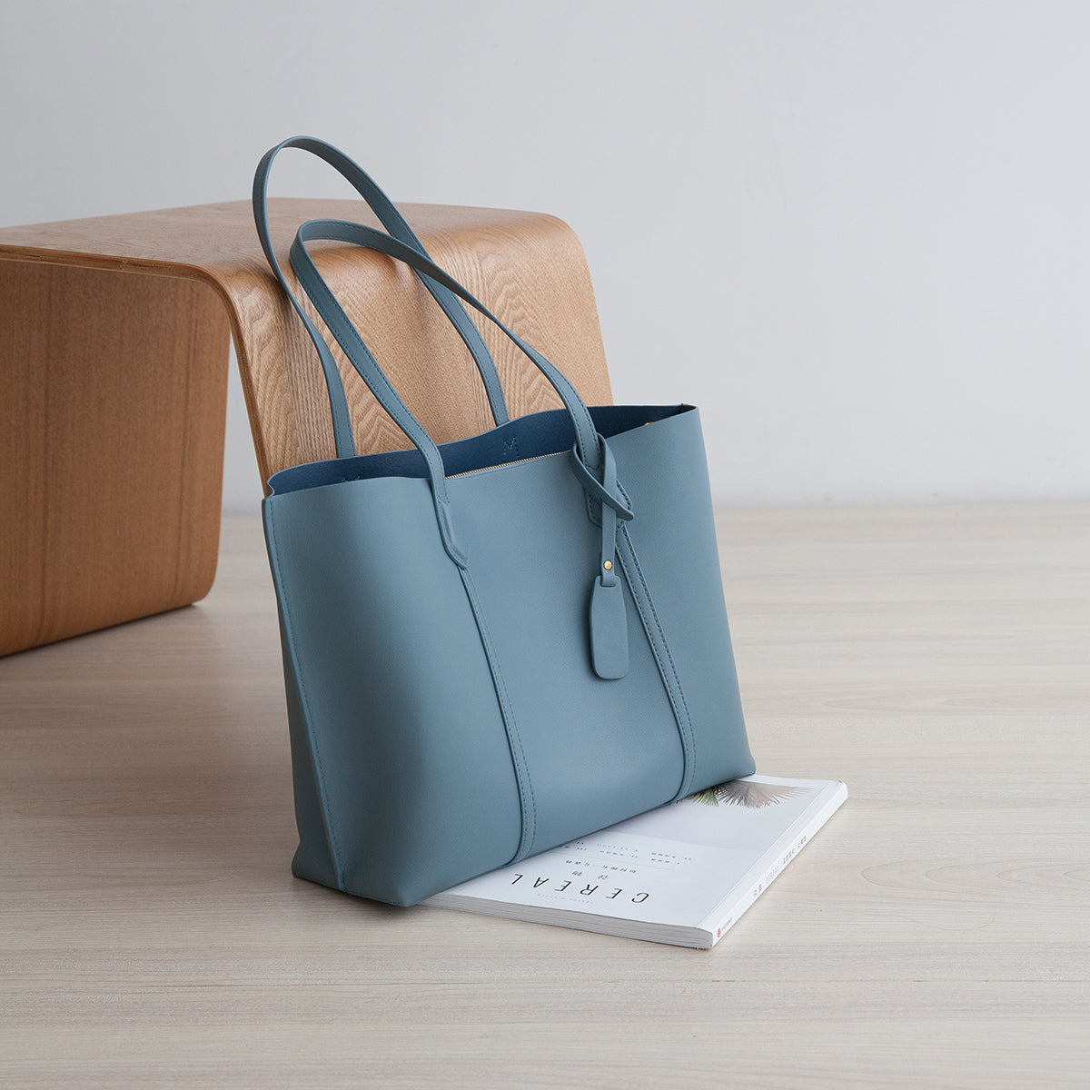 Blue tote bag on a wooden surface with a book underneath