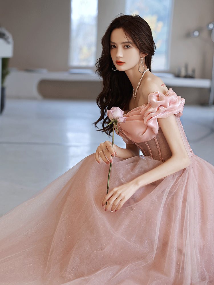 Woman in a pink dress holding flowers in an indoor setting
