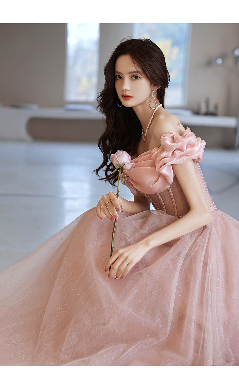 Woman in a pink dress holding a flower in an indoor setting
