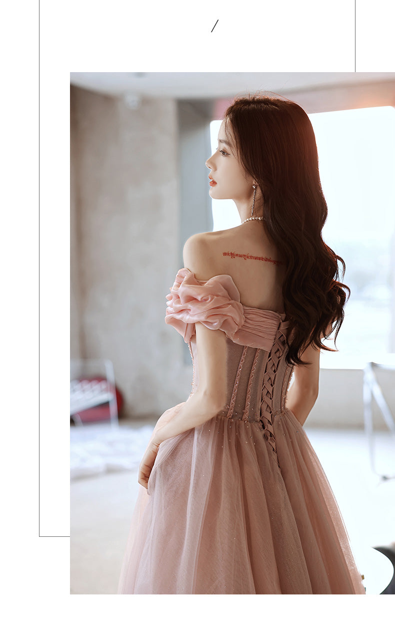 Woman in a pink dress with intricate back design in a bright room.