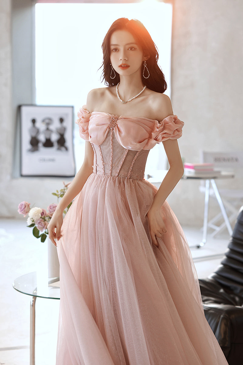 Woman wearing a pink off-shoulder dress in an indoor setting