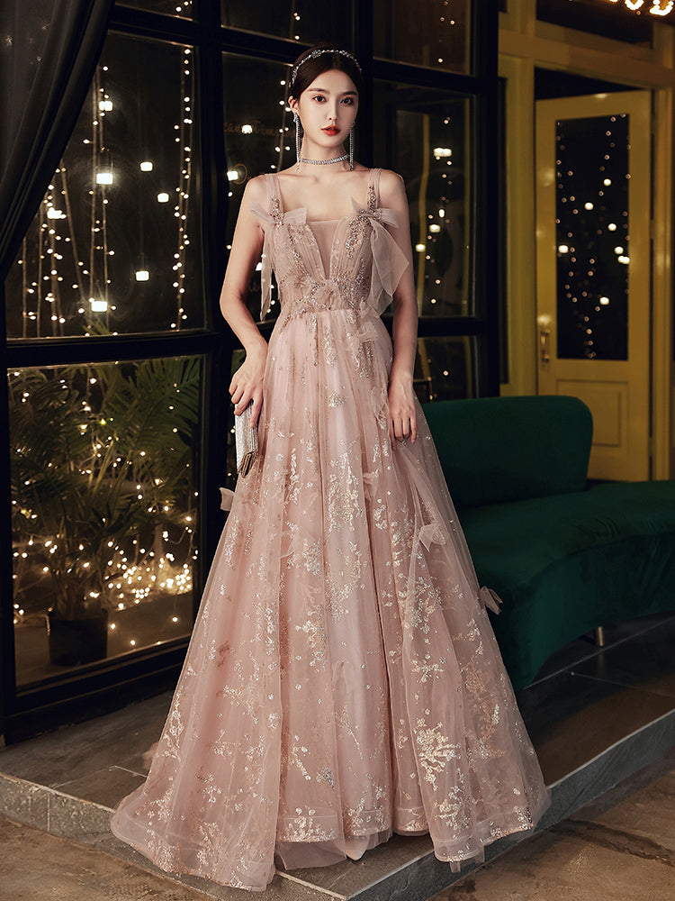 Woman in a elegant dress standing in a decorative indoor setting with lights.