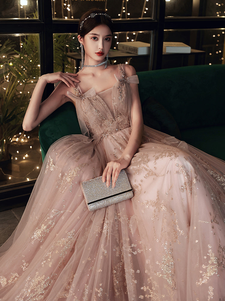 Woman in a pink evening gown with floral details sitting on a green couch.