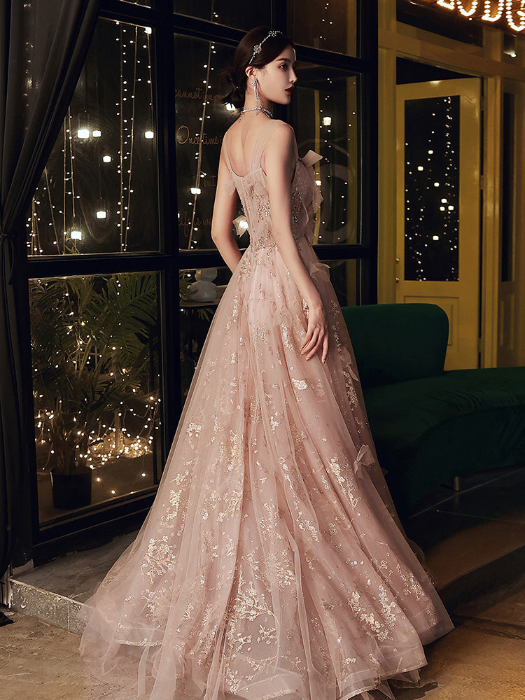 Woman in a pink lace evening gown standing in a decorated indoor setting with string lights.