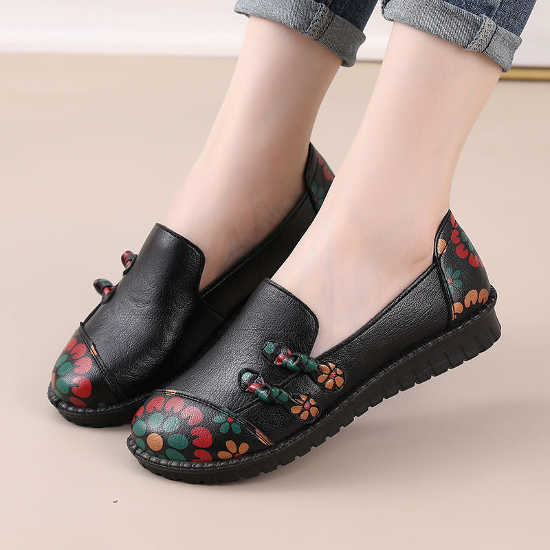 Black loafers with floral patterns on a beige background