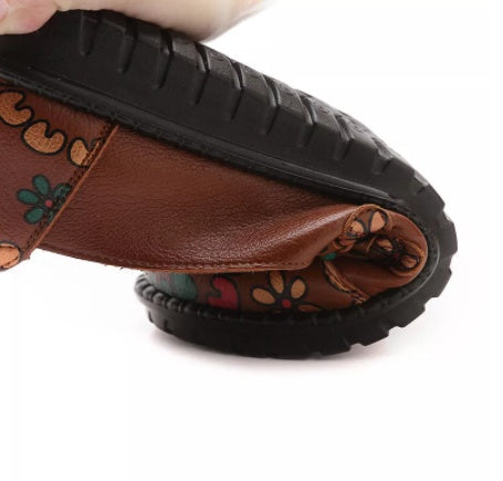 Close-up of a brown sandal with floral patterns on a white background
